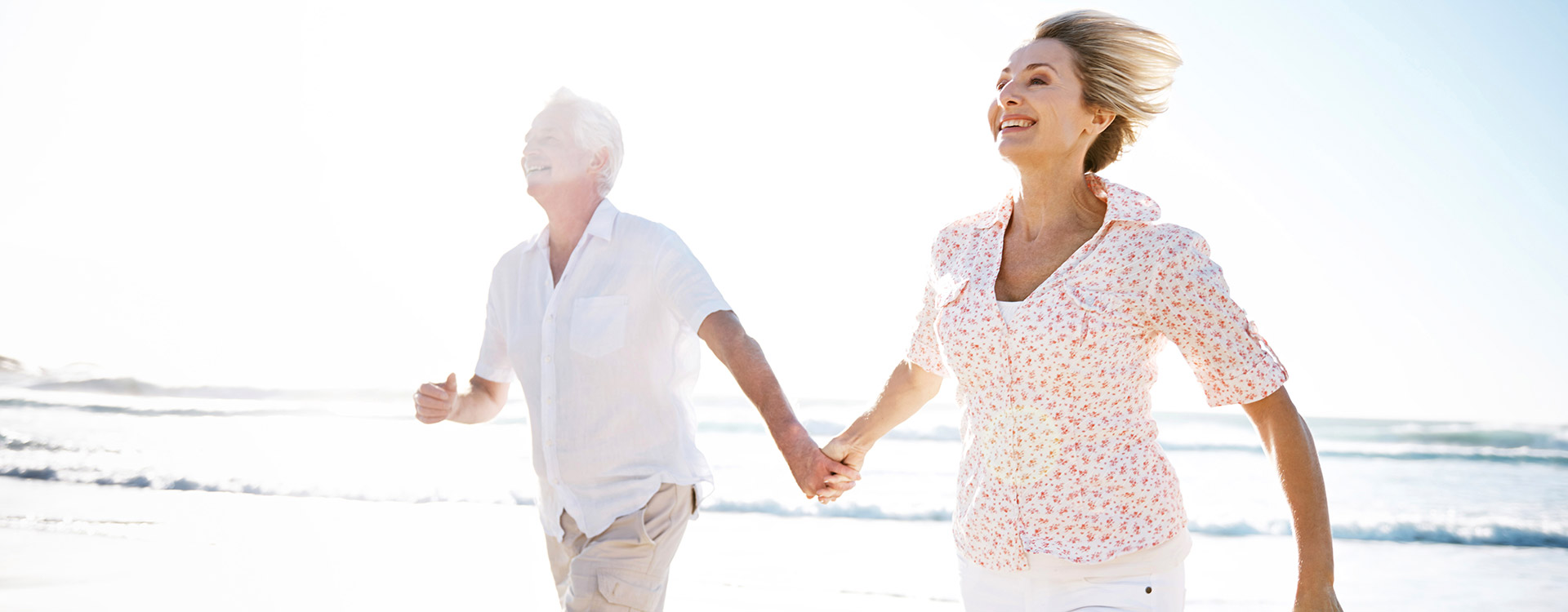 Älteres Paar läuft fröhlich über den Strand